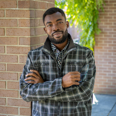 Abdul Osman smiles at the camera. He's in an outdoor setting.