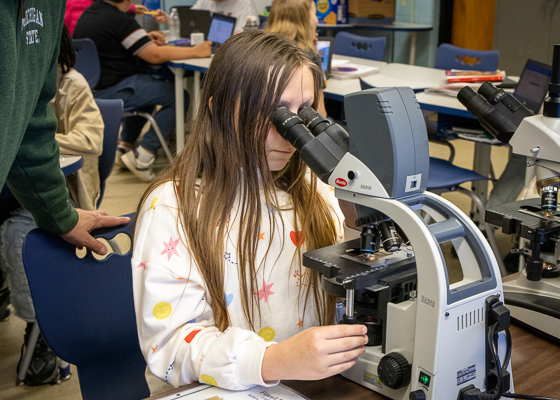 A student looks through a microscope.