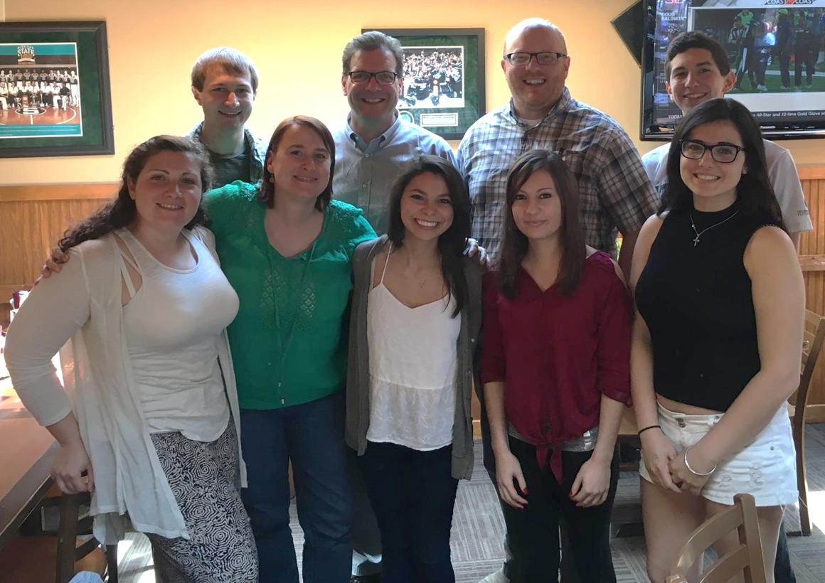 A group of people stand together at a restaurant.