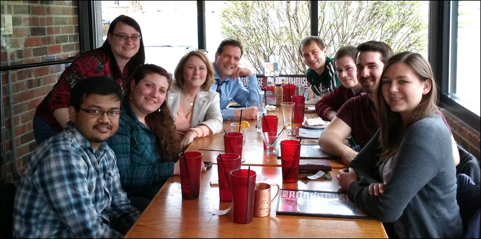 A group of people are smiling at the camera. They are at a restaurant.