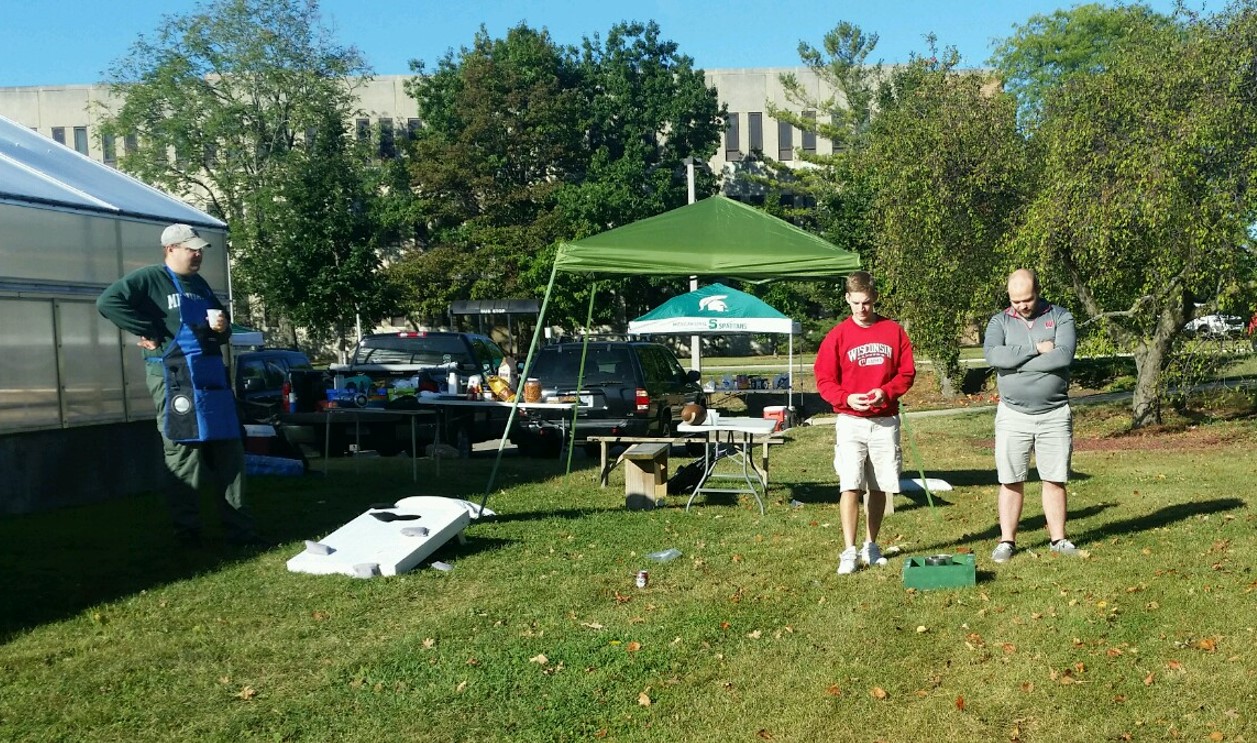 Two people play the washer toss game at the tailgate.