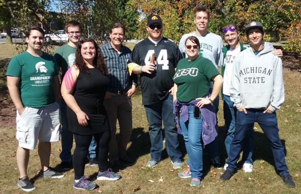 A group of people stand together and smile at the camera.