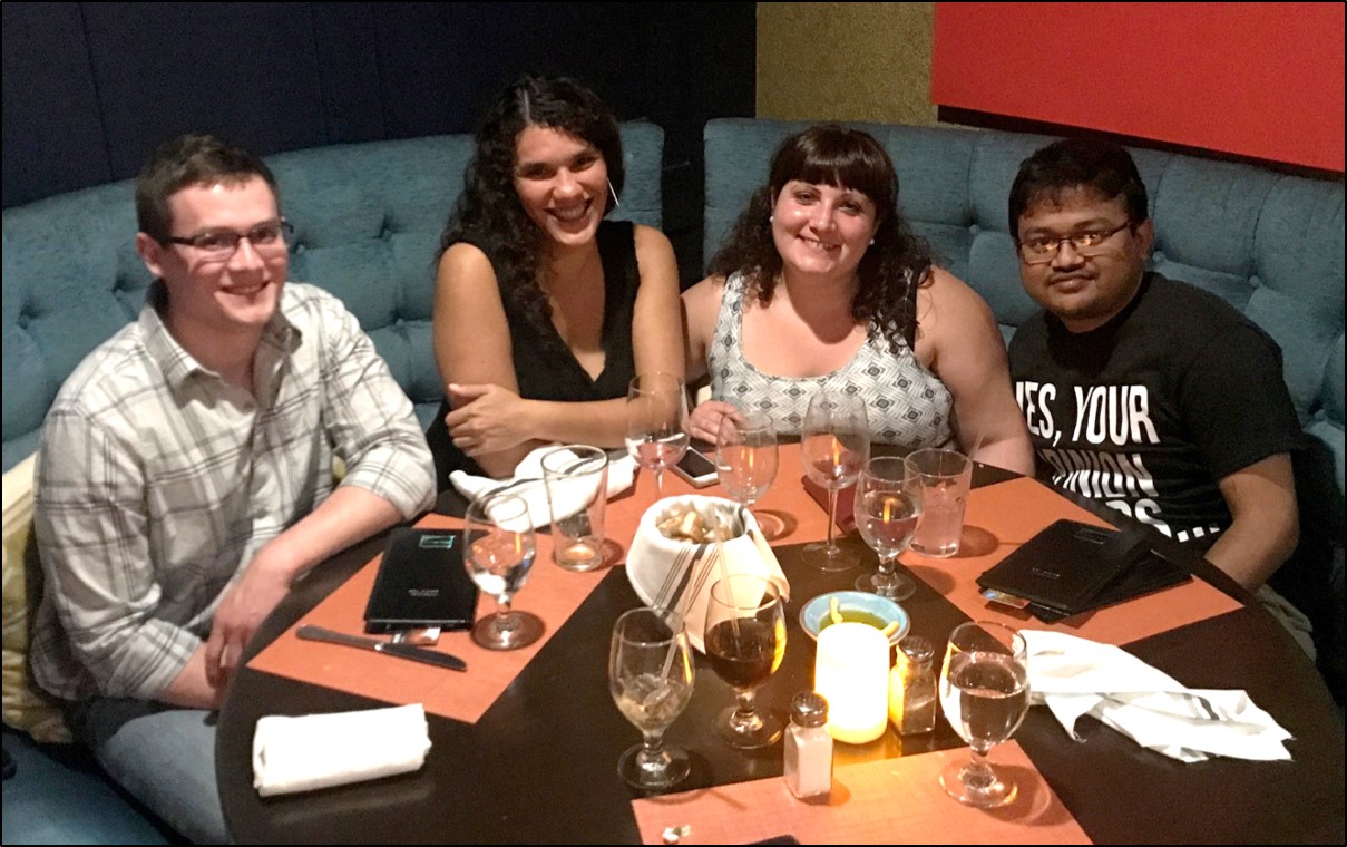 Four people sit at a table at a restaurant.