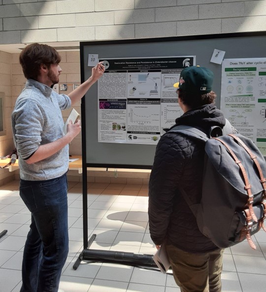 Dylan explaining his research to a showcase attendee.