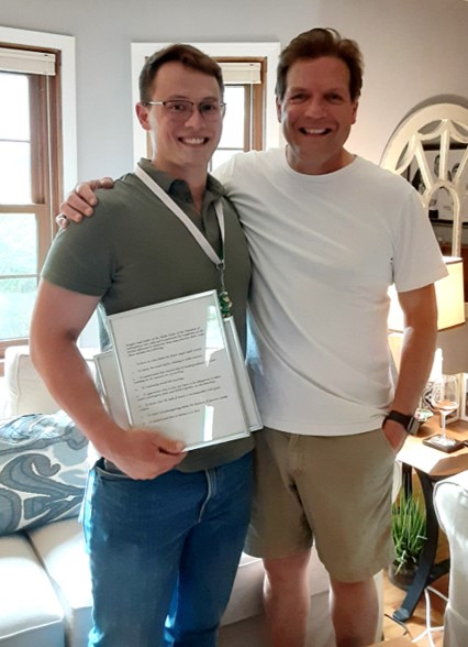 Lucas and Vic stand in Vic's house. Lucas is holding something framed in his hand.